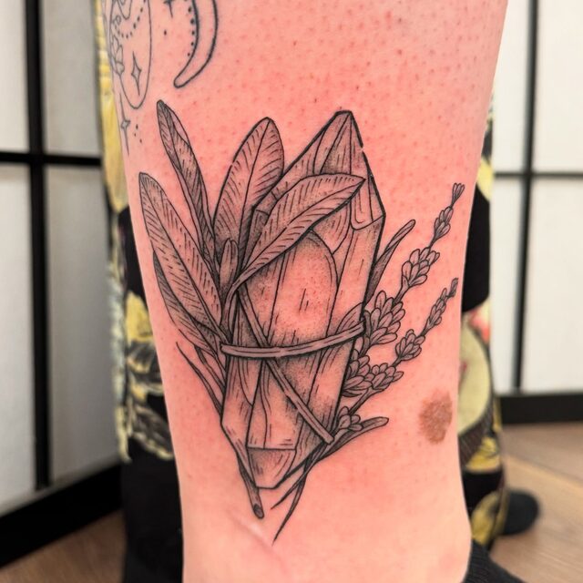 Tattoo of a crystal bound with sage leaves and sprigs of lavender