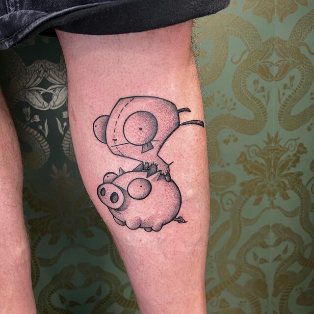 Tattoo of GIR from Invader Zim in a dog costume sitting on a pig, on a leg