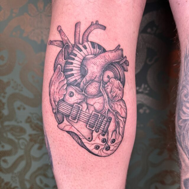 Anatomical heart woven with a guitar and piano keys, tattooed on a calf