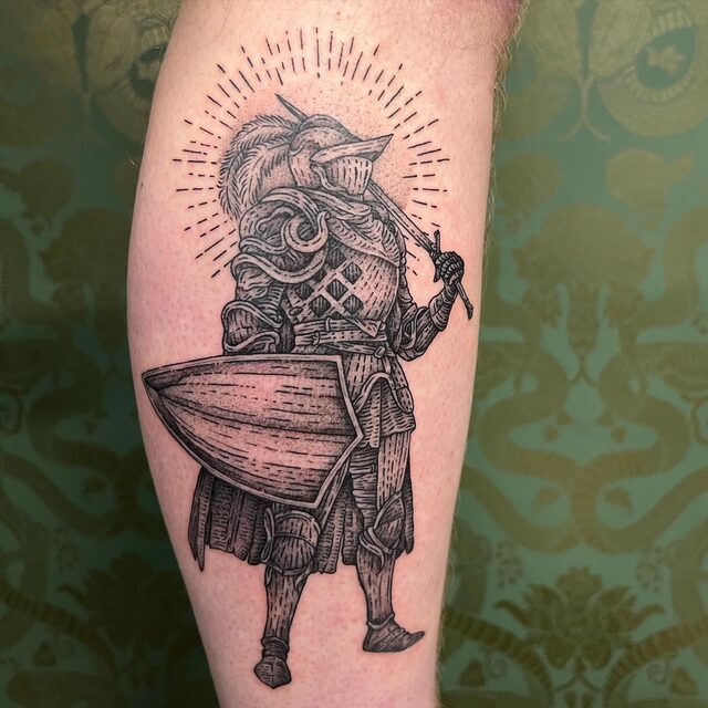 Etched tattoo of an armored knight with a plumed helmet, a long shield and a sword, on a calf