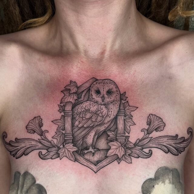 Chest piece of an owl perched between two pillars with baroque scrollwork on either side