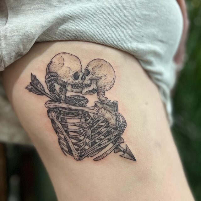 Etched tattoo of two skeletons embracing and kissing, pierced by an arrow, on the ribs