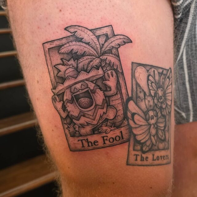 Two tarot card tattoos on an upper arm: The Fool with Alolan Exeggutor and The Lovers with Butterfree